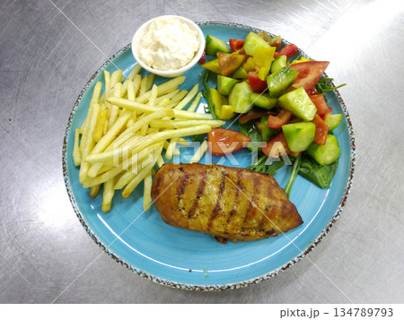 Grilled chicken breast and French fries with a fresh vegetable salad Grilled chicken breast and French fries with a fresh vegetable salad 134789793