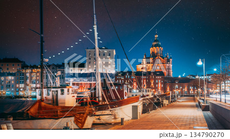 Helsinki, Finland. Pier With Boats, Pohjoisranta Street And View Of Uspenski Cathedral In Evening Night Illuminations. Night stars shining above street 134790270