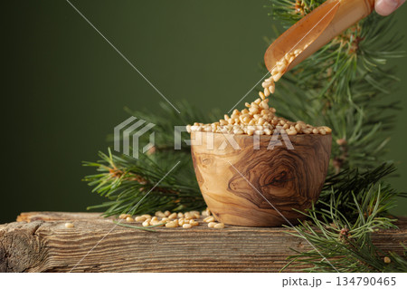 Pine nuts is poured in a wooden bowl. 134790465