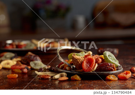 Dried tropical fruits, nuts, and raisins on a kitchen table. 134790484