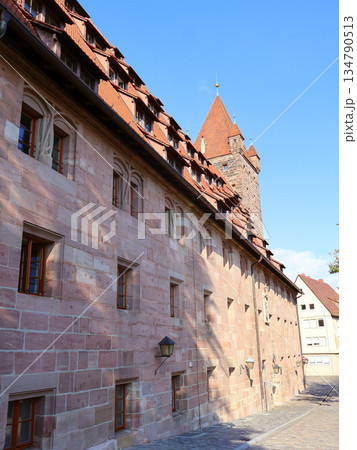 Historic Stone Building With Red Tile Roof And Tower Along Cobblestone Street in Nuremberg 134790513