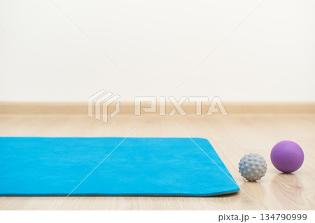 Yoga mat and fascia massage balls arranged on wooden floor for fitness 134790999