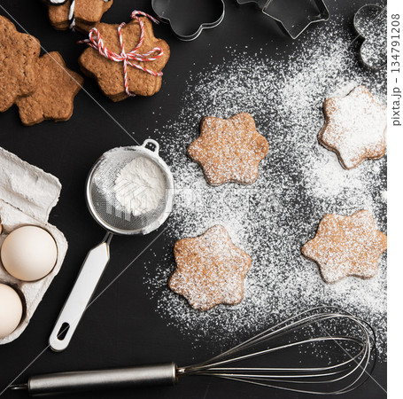 Star-shaped gingerbread cookies, sprinkled powdered sugar, metal sieve, whisk, chicken egg in a package Star-shaped gingerbread cookies, sprinkled powdered sugar, metal sieve, whisk, chicken egg in a package 134791208