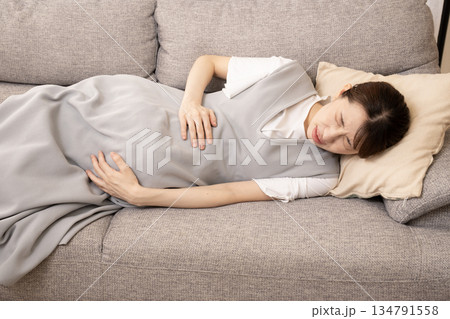 ソファーに横たわって痛がる妊婦の女性 ソファーに横たわって痛がる妊婦の女性 134791558