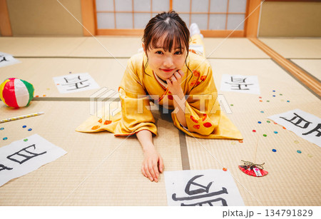和室で書道の作品を置き横になる若い着物の女性 134791829