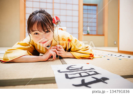 和室で書道の作品を置き横になる若い着物の女性 134791836