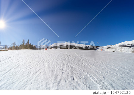Wide Empty Ski Slope with Sunbeams in Winter Mountains 134792126