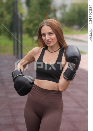 A Caucasian woman practices boxing outdoors.  134792884