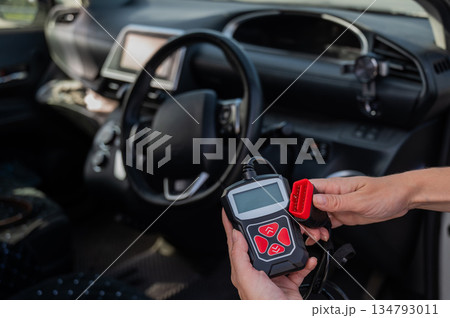Woman using OBD2 diagnostic scanner. Woman using OBD2 diagnostic scanner. 134793011