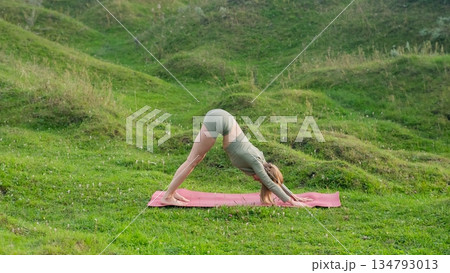 Caucasian woman doing yoga outdoors. Downward facing dog. Caucasian woman doing yoga outdoors. Downward facing dog. 134793013