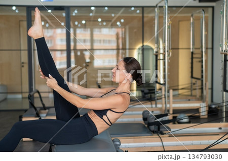 Caucasian woman doing exercises on reformer machine.  134793030