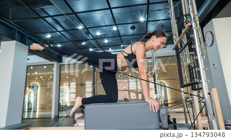 Caucasian woman doing leg exercise on reformer machine. Caucasian woman doing leg exercise on reformer machine. 134793048