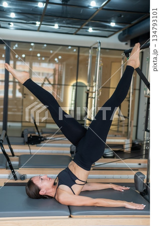 Caucasian woman doing leg exercise on reformer machine. Caucasian woman doing leg exercise on reformer machine. 134793101