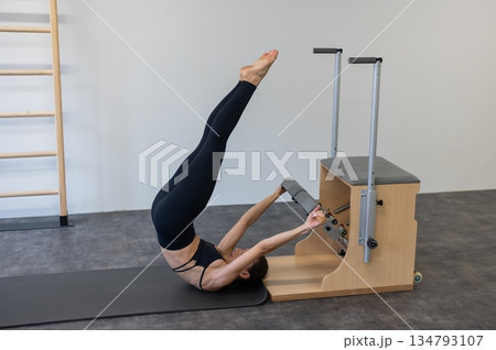 Caucasian woman doing Pilates on classic chair. Caucasian woman doing Pilates on classic chair. 134793107