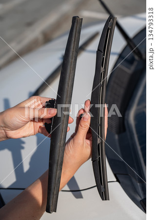 Close up of female hands changing windshield wipers. Close up of female hands changing windshield wipers. 134793318