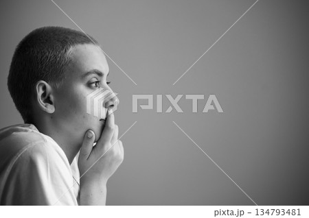Portrait of a sad young woman sitting at a table on a white background. Copy space 134793481