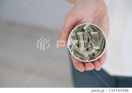 A woman holds a jar of chewing tobacco.  134793486