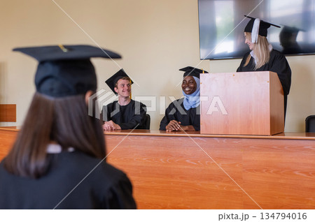 A young woman stands at the lectern and delivers a graduation speech to her classmates.  134794016