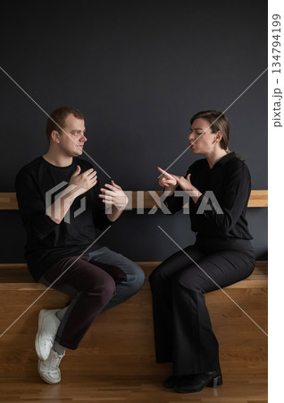 A man and a woman are talking in Russian sign language.  134794199