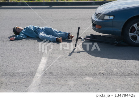A Caucasian woman on a scooter after being hit by a car. 134794428