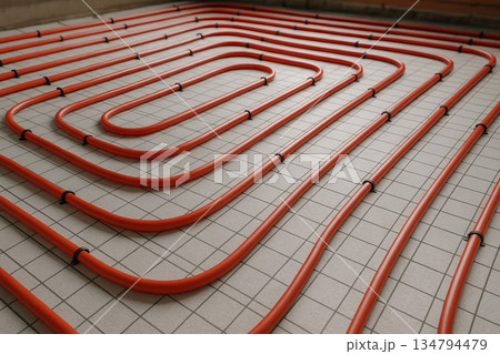 Underfloor heating installation with red pipes arranged in spiral pattern on tiled floor. concept of modern home heating, energy efficiency, interior comfort 134794479