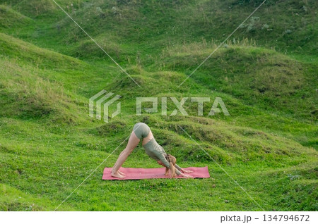 Caucasian woman doing yoga outdoors. Downward facing dog. Caucasian woman doing yoga outdoors. Downward facing dog. 134794672