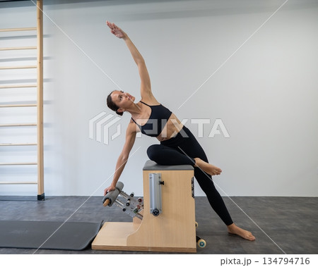 Caucasian woman doing Pilates on classic chair. Caucasian woman doing Pilates on classic chair. 134794716