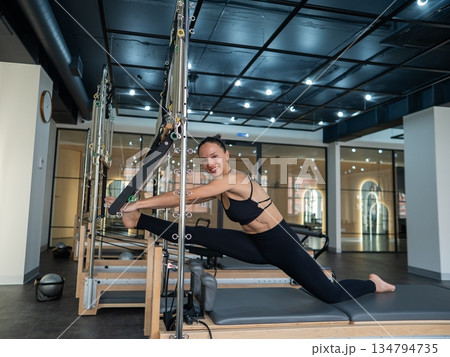 Caucasian woman doing splits on reformer. Caucasian woman doing splits on reformer. 134794735