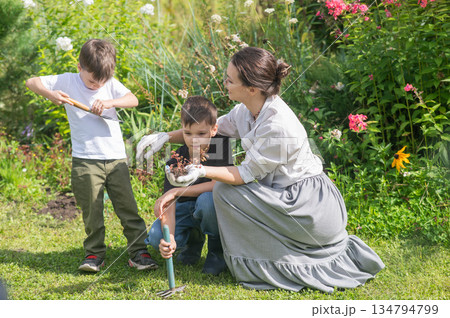 Caucasian woman tending her garden with her sons.  134794799