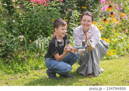 Caucasian woman tending her garden with her son.  134794808