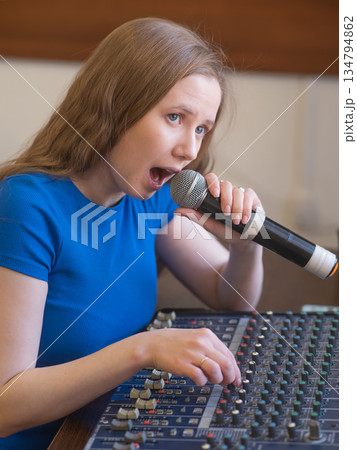 Young woman mixing live sound. Girl recording a song in the studio. Young woman mixing live sound. Girl recording a song in the studio. 134794862