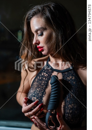Beautiful brunette in lace lingerie holds black dildo. Beautiful brunette in lace lingerie holds black dildo. 134794878