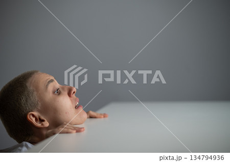 A Caucasian woman with short hair peeks out from under a table.  134794936