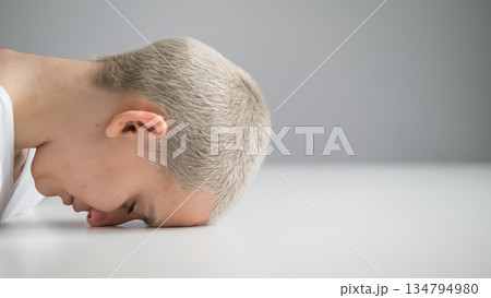 Sad woman sitting with her head on the table on a white background. 134794980