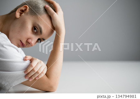 Portrait of a sad young woman sitting at a table on a white background. Copy space Portrait of a sad young woman sitting at a table on a white background. Copy space 134794981