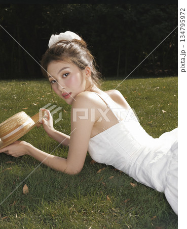 Woman is laying on the grass with a straw hat on her head 134795972