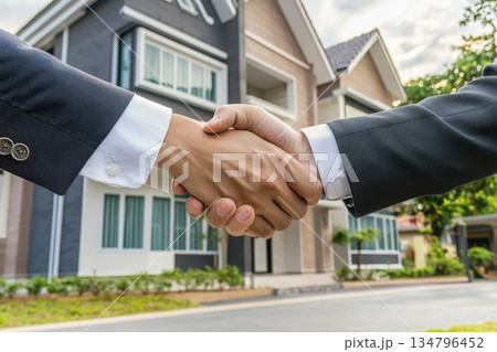 Business professionals shake hands in front of modern real estate property for successful deal 134796452