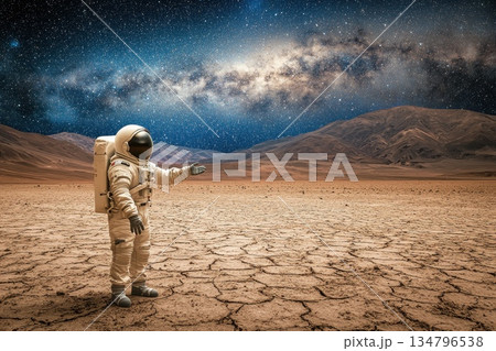 Astronaut Extending Hand Toward Viewer on Dry Planet Landscape Under Starry Sky Astronaut Extending Hand Toward Viewer on Dry Planet Landscape Under Starry Sky 134796538