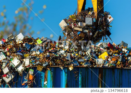 Industrial Magnet Lifting Discarded Metal Waste in a Recycling Yard Under Clear Blue Sky Industrial Magnet Lifting Discarded Metal Waste in a Recycling Yard Under Clear Blue Sky 134796618