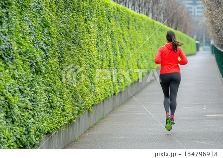 Morning Commuter Jogging Through Modern Park Path Surrounded by Greenery 134796918
