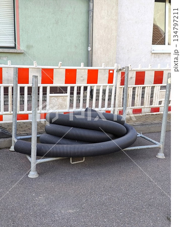 A coiled piece of corrugated pipe for cable or drainage enclosed by a construction barrier A coiled piece of corrugated pipe for cable or drainage enclosed by a construction barrier 134797211