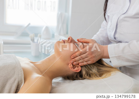 Woman having relaxing forehead massage procedure by professional beautician in cosmetology clinic 134799178