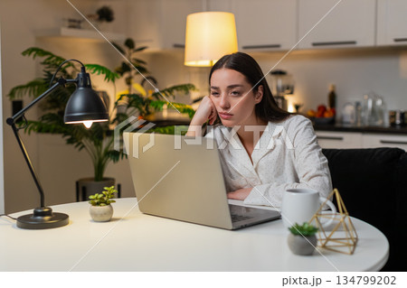 Woman at night home feels burnout stress overwork wants pause takes breath after work on laptop Woman at night home feels burnout stress overwork wants pause takes breath after work on laptop 134799202