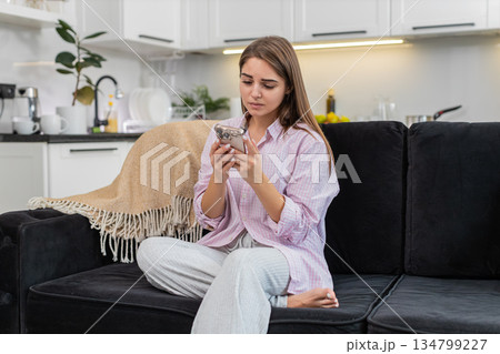 Young woman upset by game loss and job refusal sighs touches brow shakes head no holding smartphone 134799227