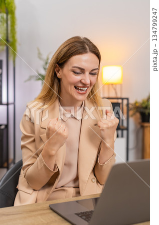 Businesswoman gets project approval message on laptop good news celebrates success victory gesture Businesswoman gets project approval message on laptop good news celebrates success victory gesture 134799247