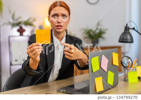 Young businesswoman stressed by sticky notes on laptop tosses notes fearing unfinished tasks today Young businesswoman stressed by sticky notes on laptop tosses notes fearing unfinished tasks today 134799270