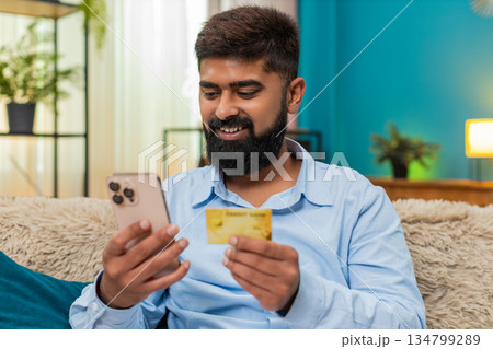 Indian man enters credit card number for secure online purchase on smartphone careful happy shopping 134799289