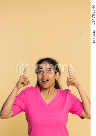 Indian woman seriously pointing finger upwards, indicating important message or announcement above Indian woman seriously pointing finger upwards, indicating important message or announcement above 134799340