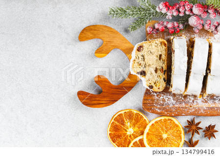 Traditional sliced Christmas stollen loaf with raisins and powdered sugar on wooden cutting board 134799416