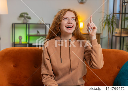 Thoughtful inspired woman make positive gesture raises finger came up with creative idea at home 134799672